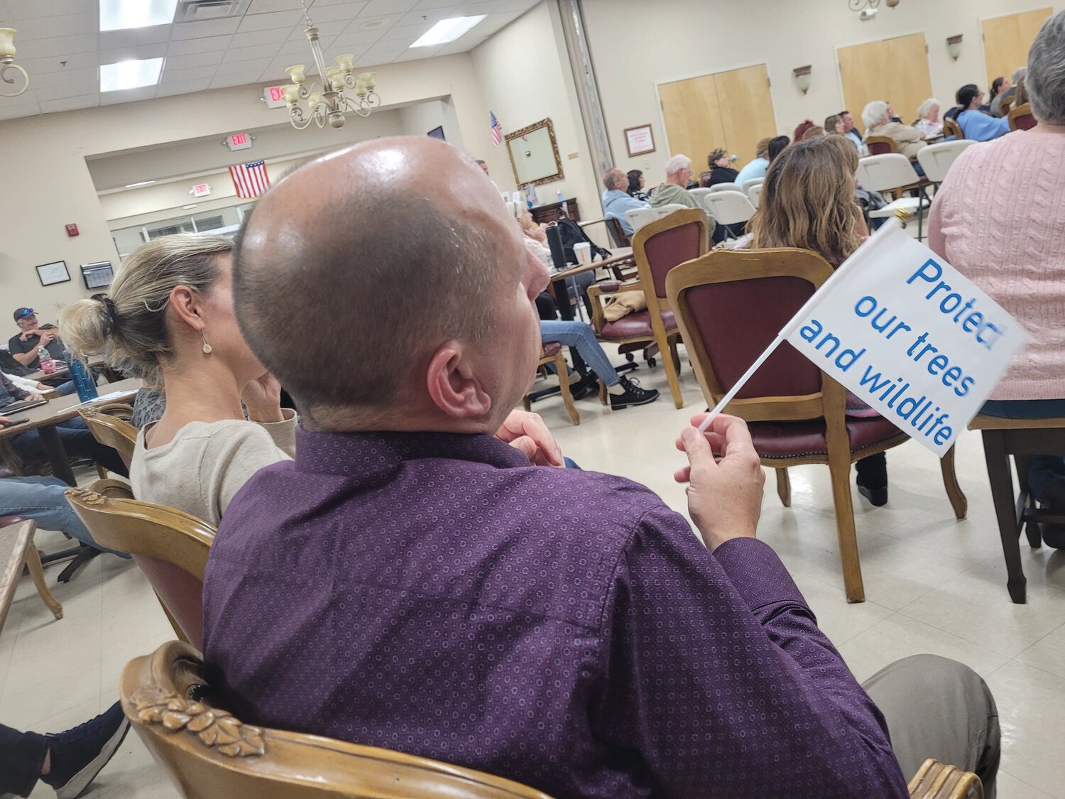 SIGNS OF THE TIMES: Johnston residents held tiny flags decrying “Not In My Backyard” and urging the board to “Protect Our Trees and Wildlife.”
